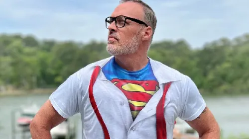 Business man poses in front of lake with super hero shirt
