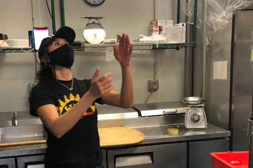 Small business owner Melissa Maese Goldberg flipping pizza dough for her pizza shop