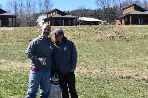 Fat sheep farm and Cabins owners pose together with pet dog