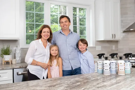 A picture of Anne Ruozzi with her husband and two children, all smiling next to Therapy Clean products.